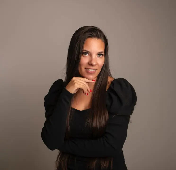 Virginia Honrubia posa de medio cuerpo mirando al frente, sonriendo y con la mano en la barbilla, proyectando seguridad, elegancia y liderazgo como profesional y formadora en el sector de la manicura y la belleza.